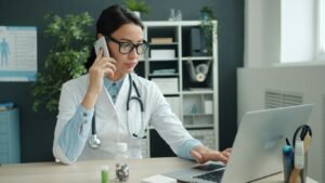 Doctor on phone, working on laptop in office.