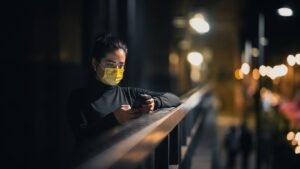 a woman wearing a face mask while looking at her cell phone