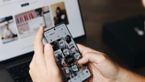 A person holding a cell phone in front of a laptop