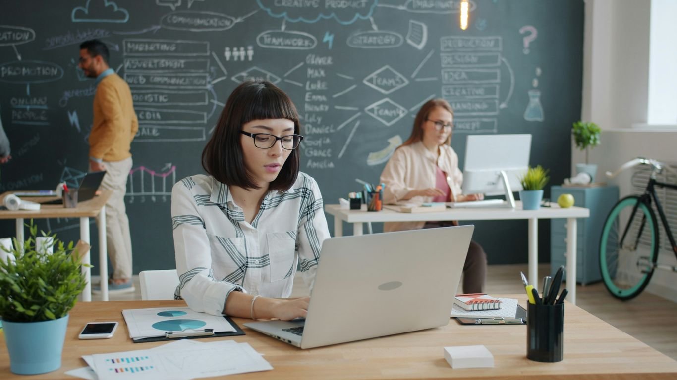People working in a modern office with a chalkboard wall.