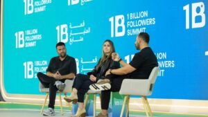 Three people sit on chairs on a stage discussing.