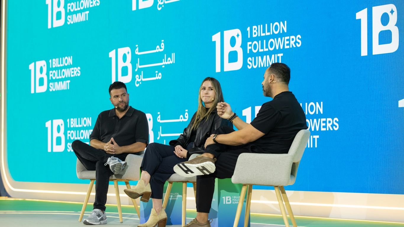 Three people sit on chairs on a stage discussing.