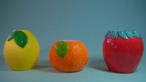 Three ceramic fruit-shaped planters on a blue background