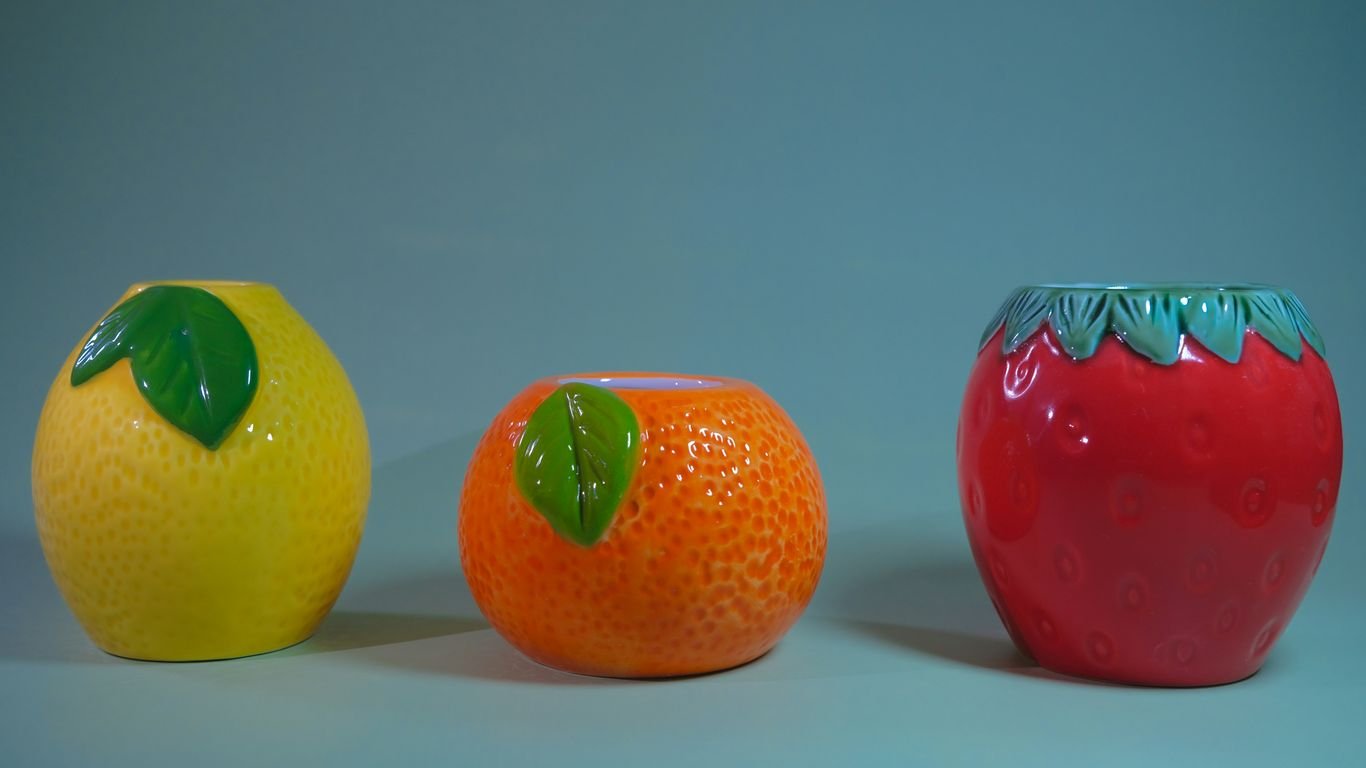 Three ceramic fruit-shaped planters on a blue background