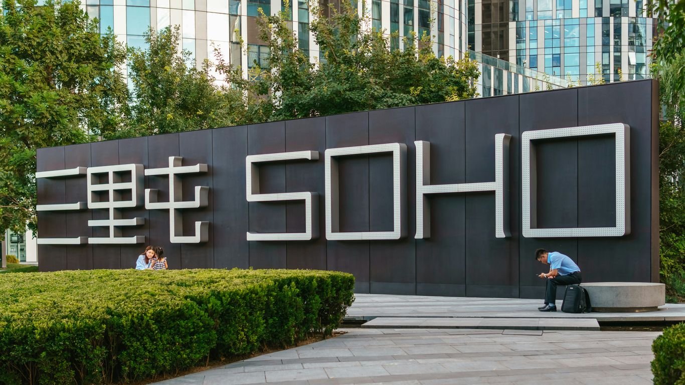 A man sitting on a bench in front of a sign