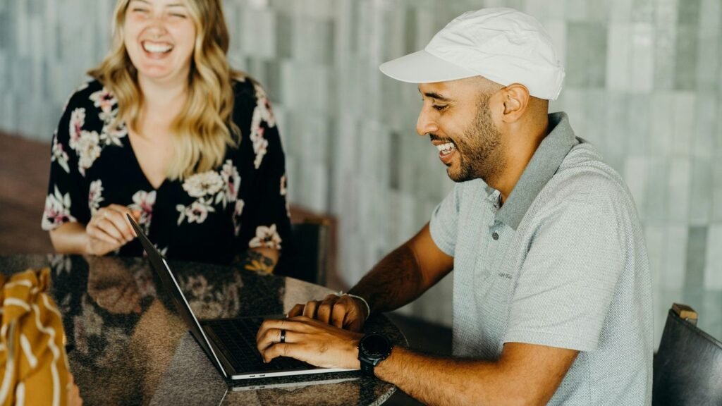 a man and a woman sitting at a table with a laptop