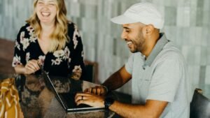 a man and a woman sitting at a table with a laptop