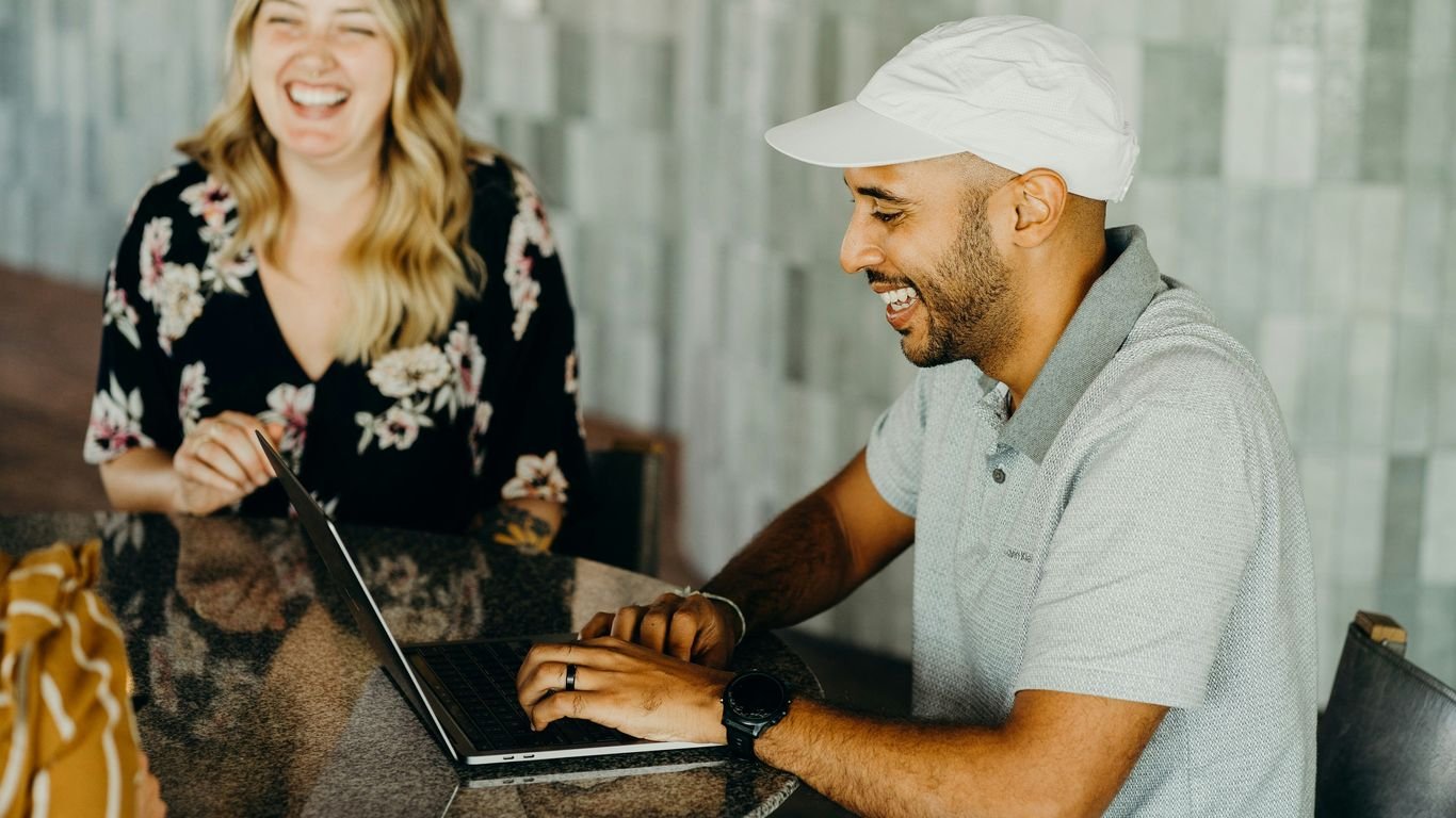 a man and a woman sitting at a table with a laptop
