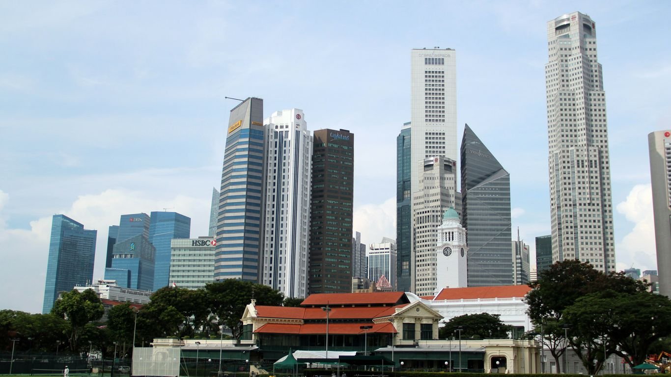 white and gray concrete building near green grass field under white sky during daytime