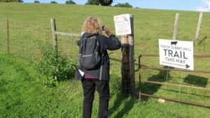 a woman taking a picture of a trail sign