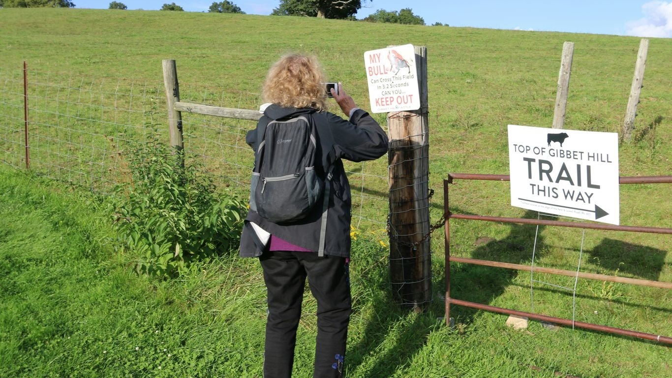 a woman taking a picture of a trail sign