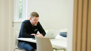 Man working on laptop at a white table.