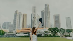 a woman in a white dress holding up a black object in front of a city