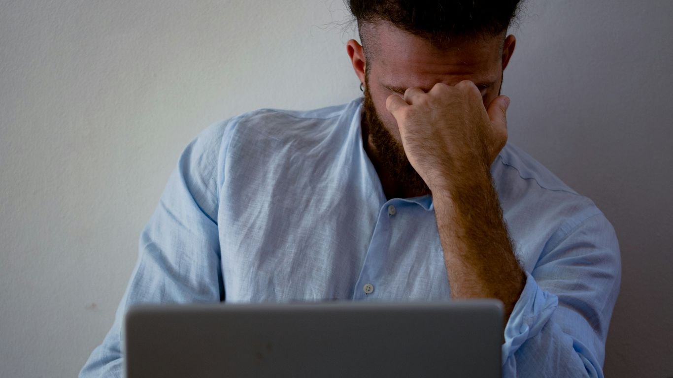 man in blue dress shirt holding silver macbook
