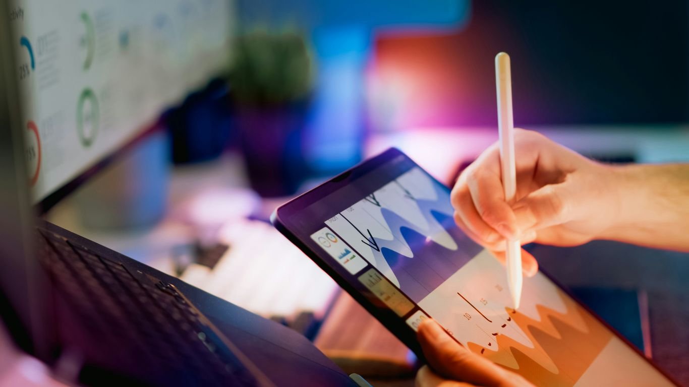Person using stylus on tablet with charts.