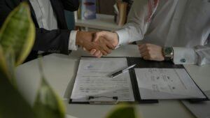 two people shaking hands over a piece of paper