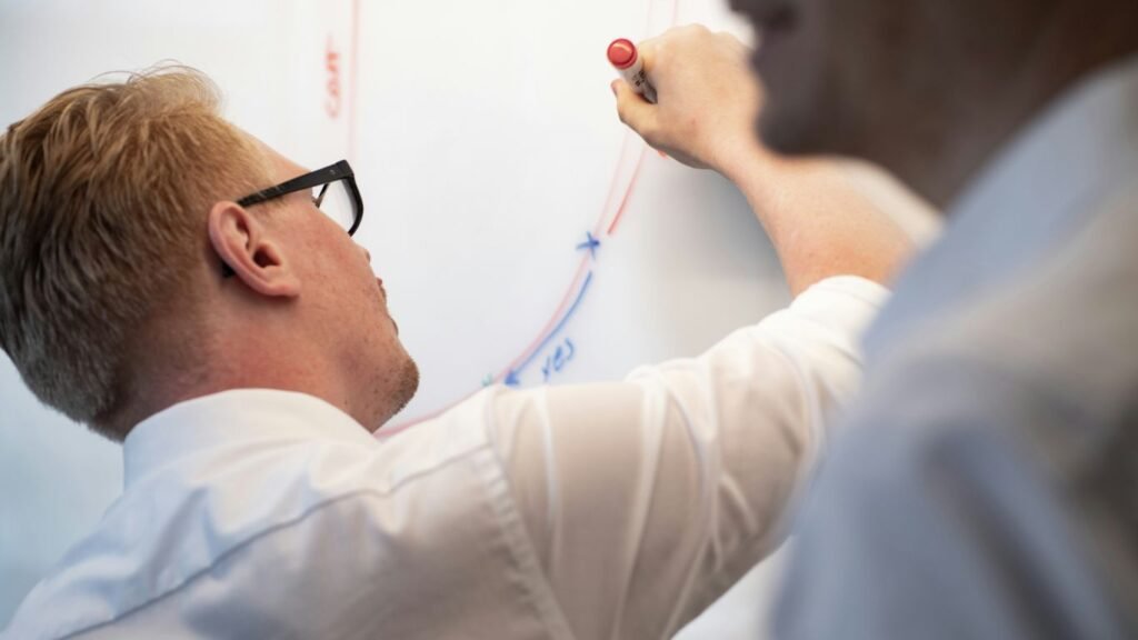 a man writing on a whiteboard with a marker