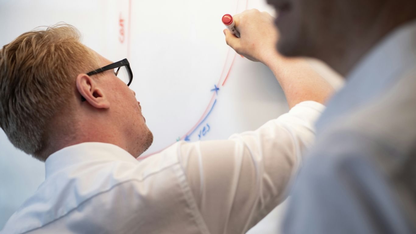 a man writing on a whiteboard with a marker