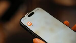 Person holding a smartphone with an app icon.