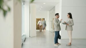 Two people talking in a modern office hallway.