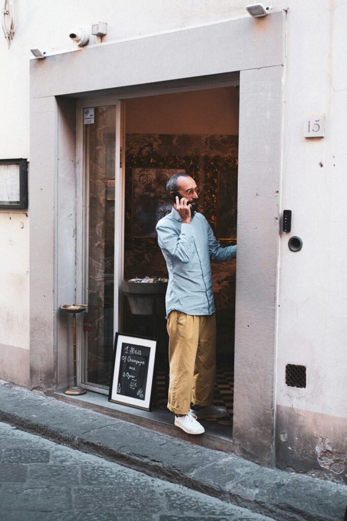 Singapore small business owner answering a customer call at the shop doorway, illustrating the local SEO leads a well-optimised local business profile brings in