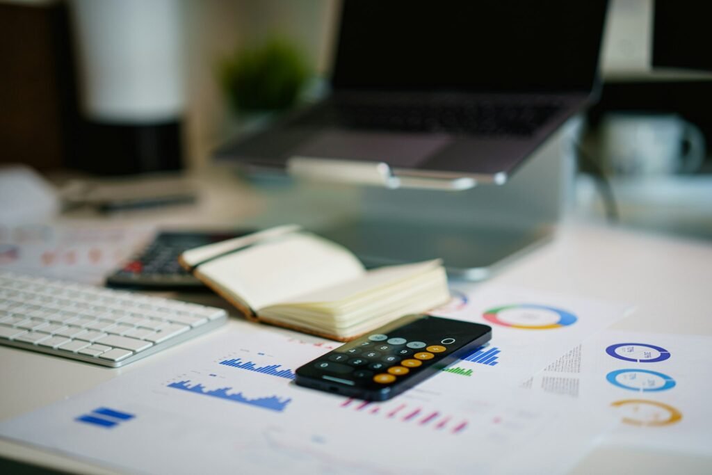 Office desk with a smartphone and financial charts showing a Singapore small business tracking its affordable digital marketing spend