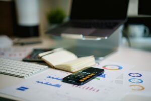 Office desk with a smartphone and financial charts showing a Singapore small business tracking its affordable digital marketing spend
