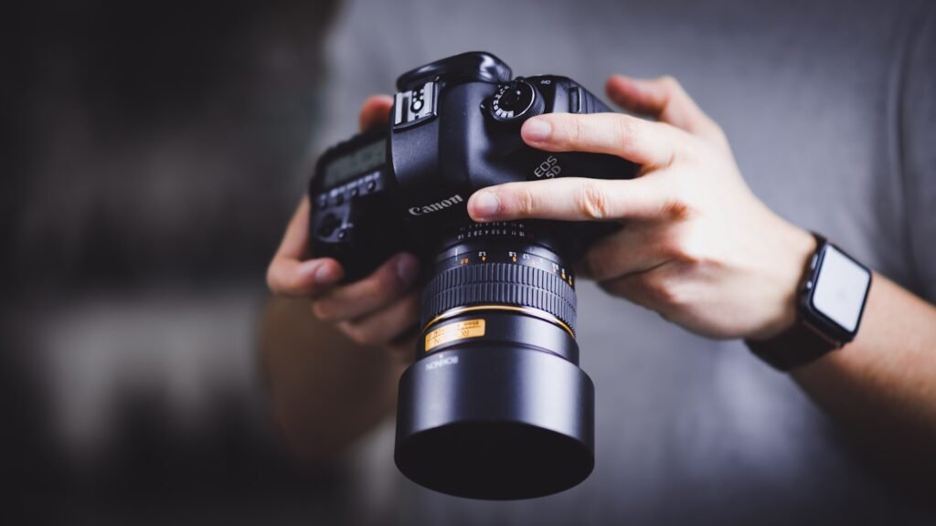 Hand holding a professional Canon DSLR camera during a commercial photography session for a Singapore business