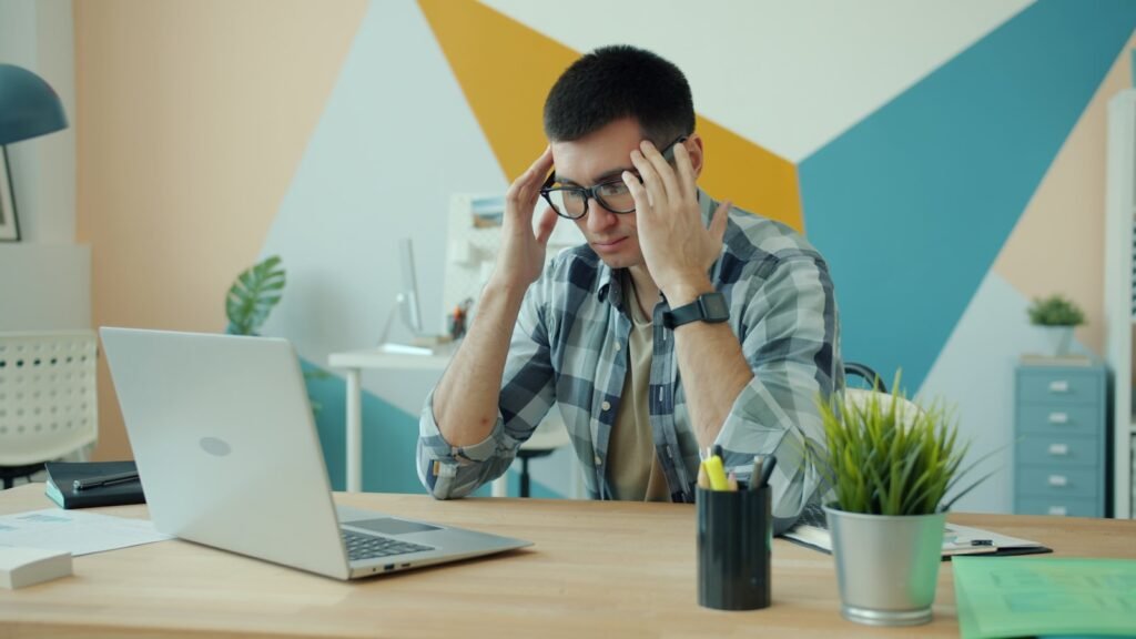 Frustrated Singapore business owner at his laptop, one of the signs it's time to hire an SEO agency