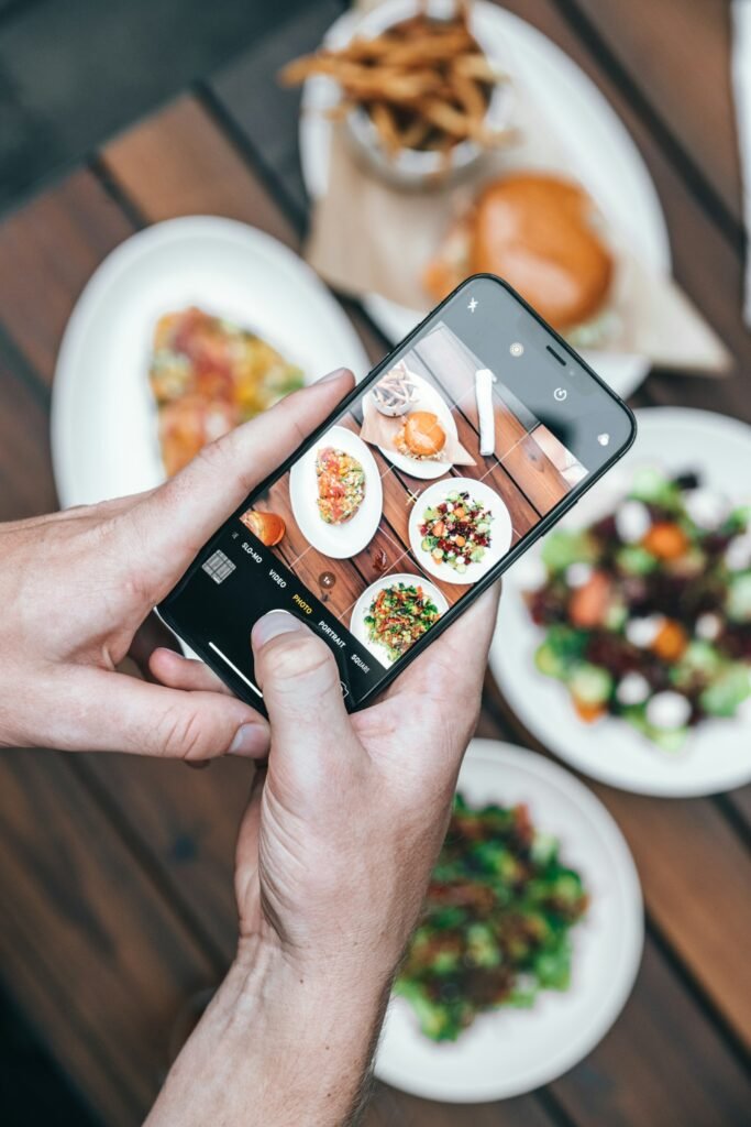 Person photographing a plate of food for social media, part of a Singapore restaurant's digital marketing