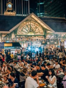 Crowded Singapore hawker centre at night with diners at communal tables, representing the restaurant customers a Singapore F&B business can reach through digital marketing