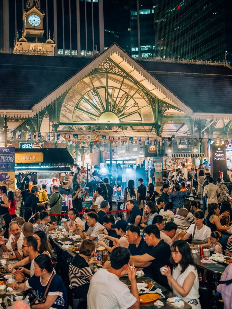 Crowded Singapore hawker centre at night with diners at communal tables, representing the restaurant customers a Singapore F&B business can reach through digital marketing