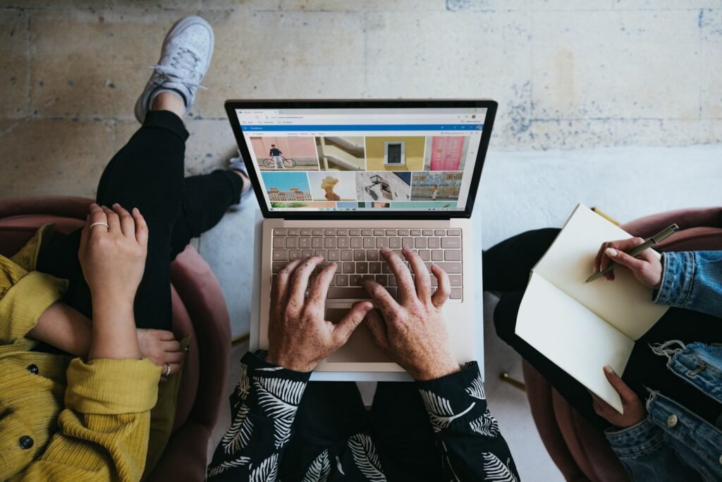 Business owner researching advertising agencies on a laptop and noting questions to ask before hiring