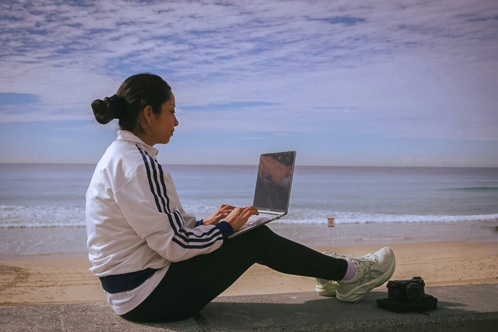 Woman working on a laptop at the beach, representing passive affiliate income