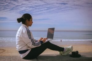 Woman working on a laptop at the beach, representing passive affiliate income