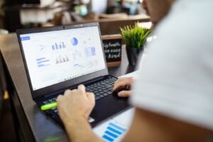 An analyst comparing competitor ad data and performance charts on a laptop during competitor ad research in Singapore.