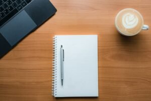 Notebook, pen and coffee on a desk, representing content marketing planning