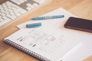 Two strategists from a design consultancy singapore team sketch wireframes on a whiteboard while a client watches from the table.