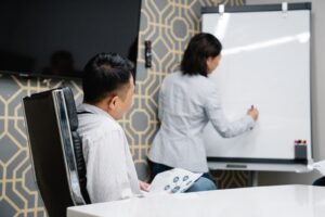 A digital consultancy Singapore session in progress, with two marketers reviewing an analytics printout against a roadmap sketched on a whiteboard.