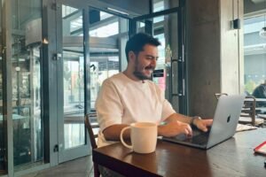 Business owner working on a laptop in a cafe, representing digital marketing services for SMEs
