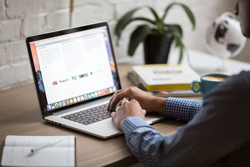 A marketer reviewing an EDM design layout on a laptop while planning an email campaign for a Singapore audience.