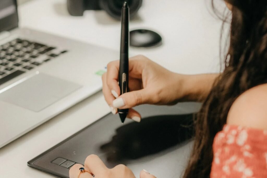Freelance graphic designer in Singapore working on client branding materials using a graphic tablet and laptop.
