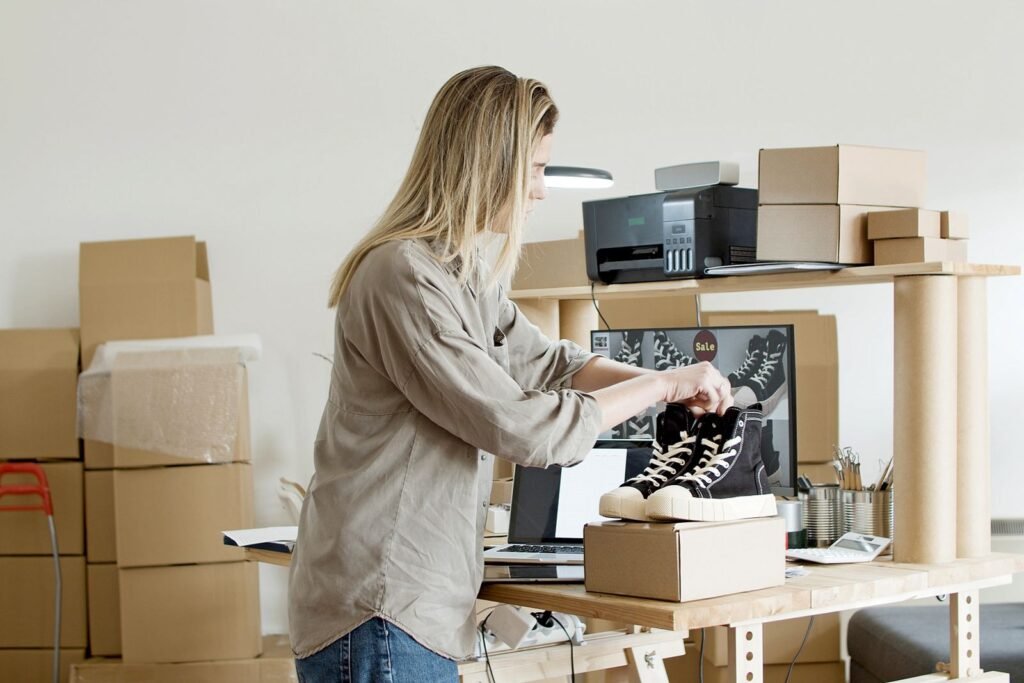A small business owner packing online orders at a desk after starting an ecommerce business in Singapore.