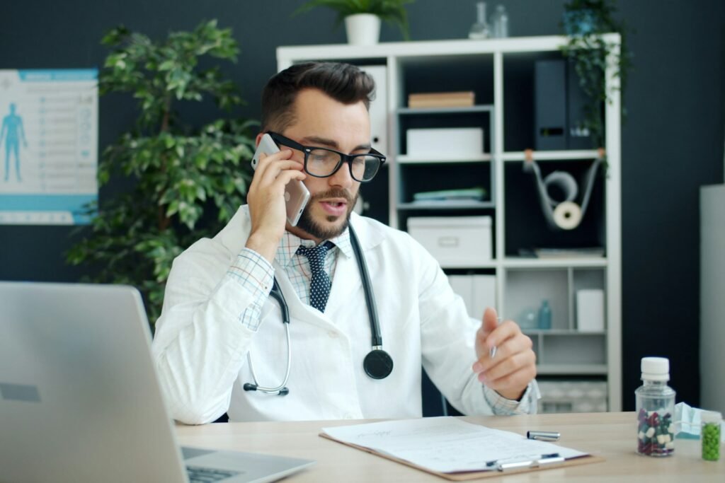 Doctor on a call at a clinic desk with a laptop, representing medical SEO for healthcare providers