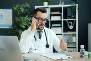 Doctor on a call at a clinic desk with a laptop, representing medical SEO for healthcare providers