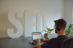 SEO specialist working at a desk beside large SEO letters
