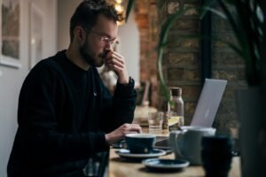 Business owner thinking at a laptop about whether SEO is worth the investment
