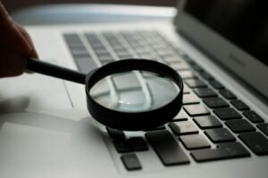 Magnifying glass over a laptop keyboard, representing the close analysis of an SEO expert